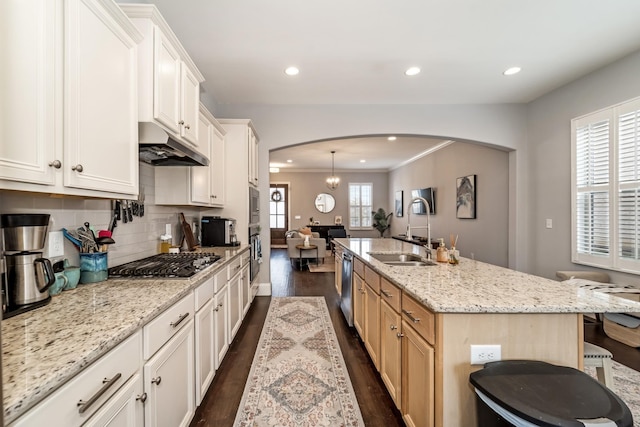 kitchen featuring tasteful backsplash, sink, a kitchen island with sink, stainless steel appliances, and light stone countertops