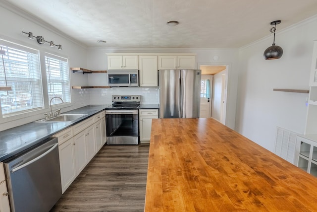 kitchen featuring sink, appliances with stainless steel finishes, butcher block counters, white cabinets, and decorative light fixtures