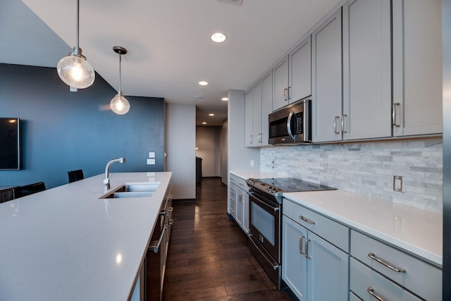 kitchen featuring pendant lighting, sink, dark wood-type flooring, stainless steel appliances, and decorative backsplash