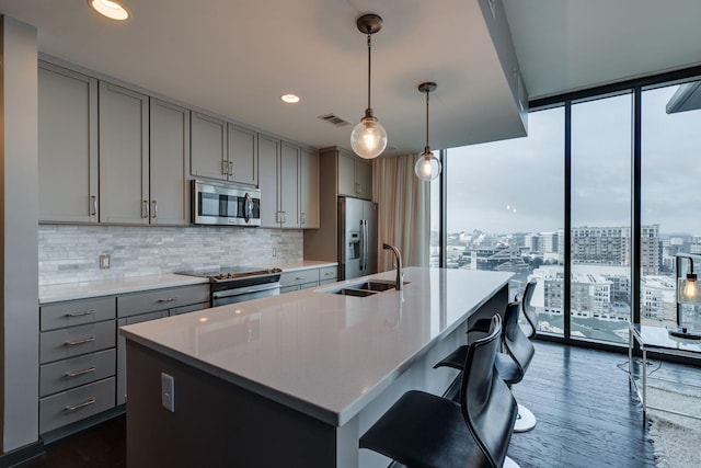 kitchen featuring gray cabinets, appliances with stainless steel finishes, floor to ceiling windows, dark hardwood / wood-style flooring, and decorative light fixtures