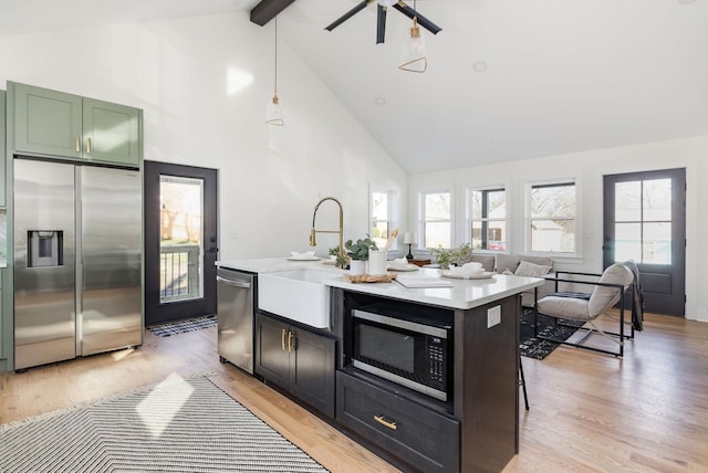 kitchen featuring sink, decorative light fixtures, appliances with stainless steel finishes, a wealth of natural light, and beam ceiling