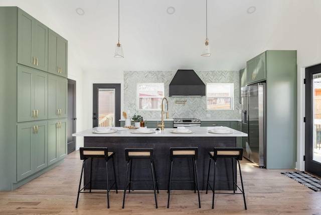 kitchen with pendant lighting, wall chimney range hood, and a healthy amount of sunlight