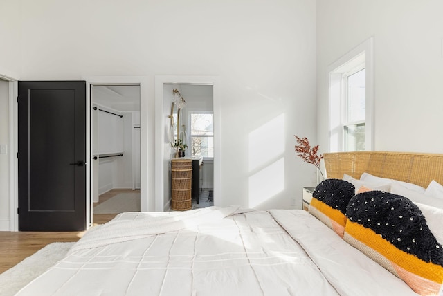 bedroom with connected bathroom, hardwood / wood-style floors, and a closet