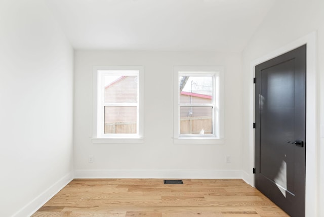 empty room with vaulted ceiling and light wood-type flooring