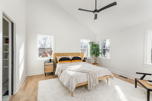 bedroom featuring multiple windows, high vaulted ceiling, ceiling fan, and light hardwood / wood-style flooring