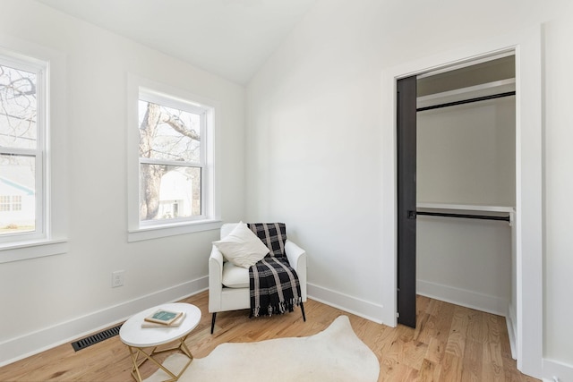 living area featuring lofted ceiling, light hardwood / wood-style floors, and a wealth of natural light