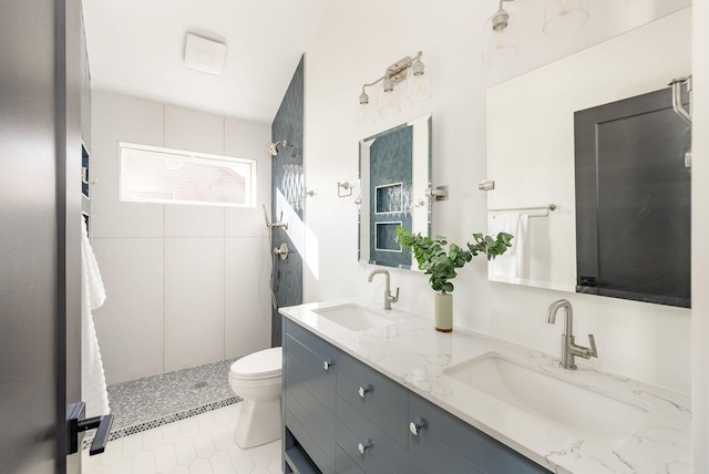 bathroom featuring tiled shower, vanity, toilet, and tile patterned flooring