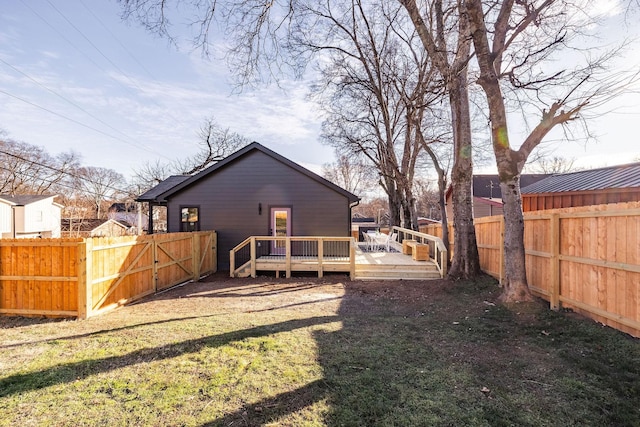 back of house featuring a wooden deck and a lawn