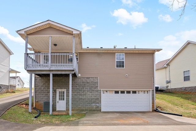 view of front of home with concrete driveway, an attached garage, a balcony, and central air condition unit