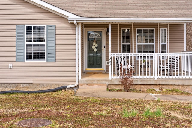 doorway to property featuring a shingled roof and a porch