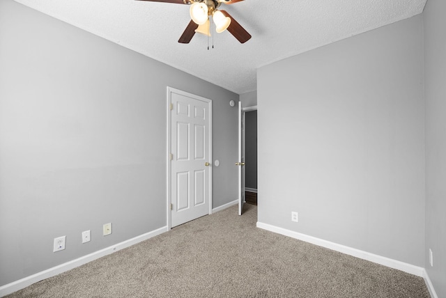 carpeted empty room featuring a ceiling fan, a textured ceiling, and baseboards