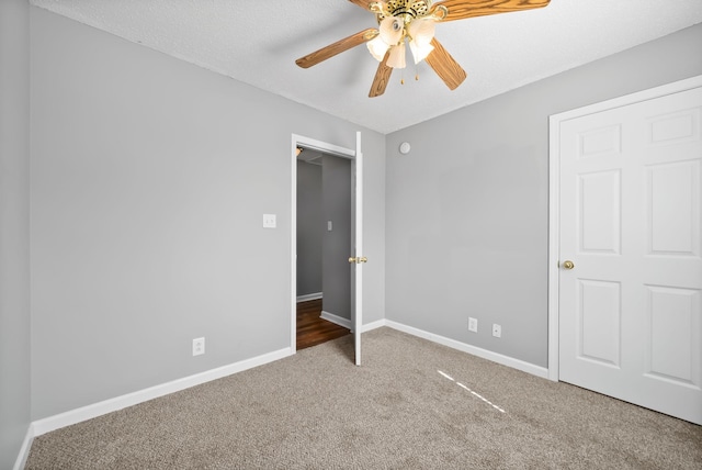 unfurnished bedroom with ceiling fan, a textured ceiling, baseboards, and carpet flooring