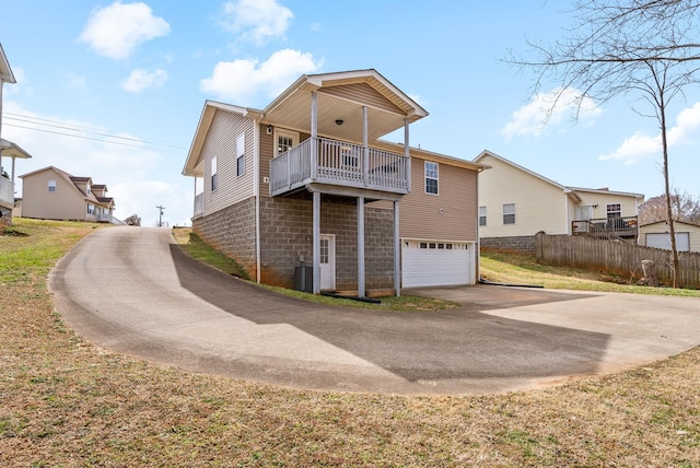 exterior space with central AC, fence, a balcony, a garage, and driveway