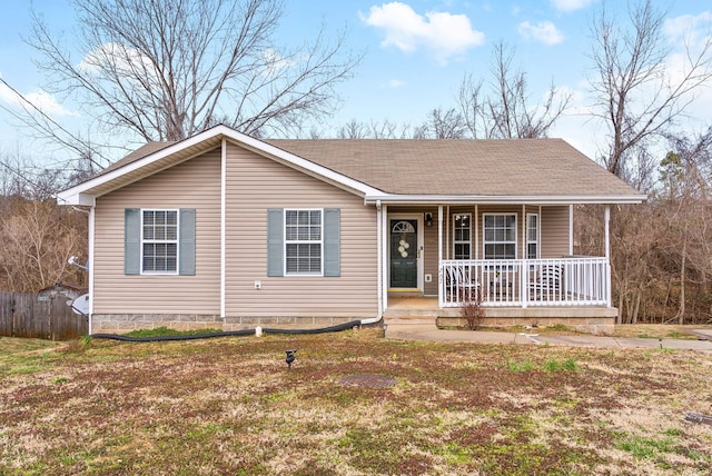 view of front of house featuring covered porch, a front lawn, a shingled roof, and fence