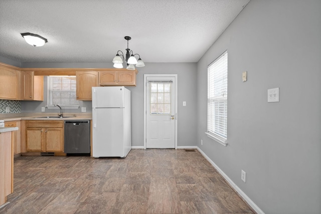 kitchen featuring a sink, baseboards, light countertops, freestanding refrigerator, and dishwasher