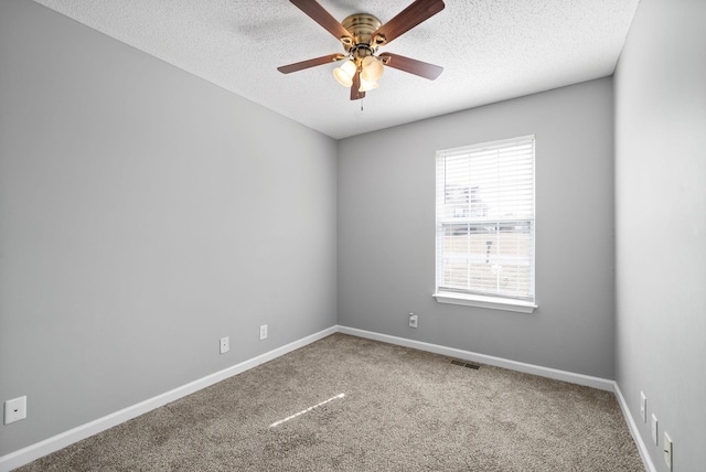 carpeted empty room featuring a ceiling fan, visible vents, baseboards, and a textured ceiling