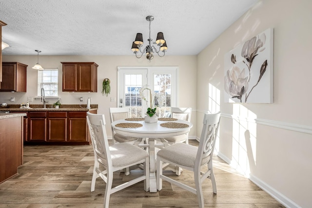 dining space featuring an inviting chandelier, hardwood / wood-style floors, sink, and a textured ceiling