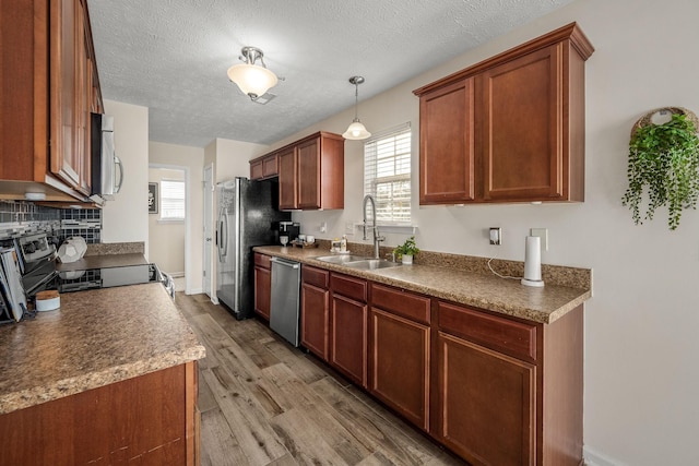 kitchen with plenty of natural light, light wood-style flooring, appliances with stainless steel finishes, and a sink