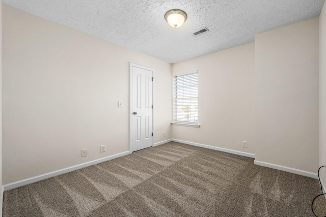 carpeted spare room featuring visible vents, baseboards, and a textured ceiling