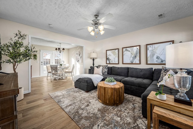 living room featuring wood-type flooring, a textured ceiling, and ceiling fan