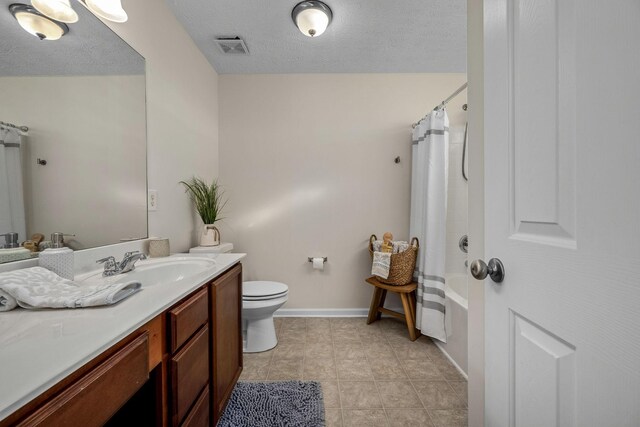 full bathroom with vanity, shower / bath combination with curtain, a textured ceiling, tile patterned floors, and toilet