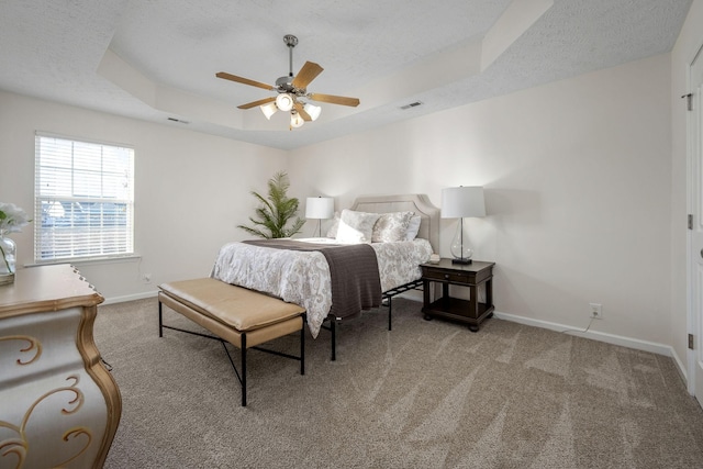 bedroom featuring a tray ceiling, baseboards, a textured ceiling, and carpet flooring