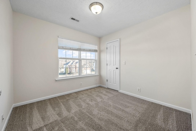 carpeted spare room featuring baseboards, visible vents, and a textured ceiling