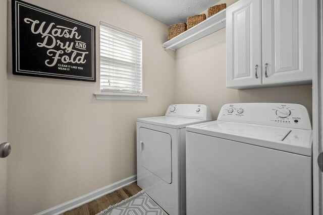 laundry room with separate washer and dryer, wood-type flooring, and cabinets