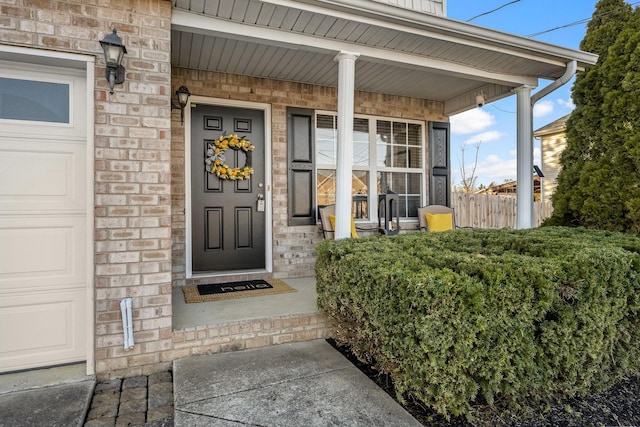 entrance to property with stone siding, a porch, and a garage