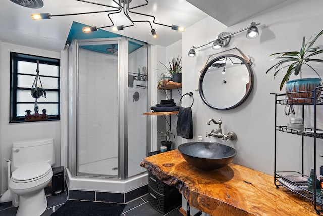 bathroom with tile patterned floors, toilet, an enclosed shower, and sink