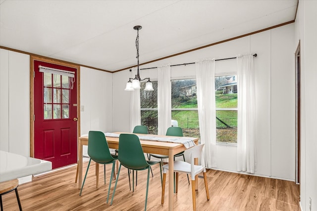 dining room with a notable chandelier, lofted ceiling, ornamental molding, and light wood-type flooring