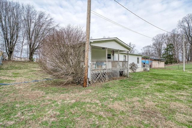 rear view of house featuring a lawn and covered porch