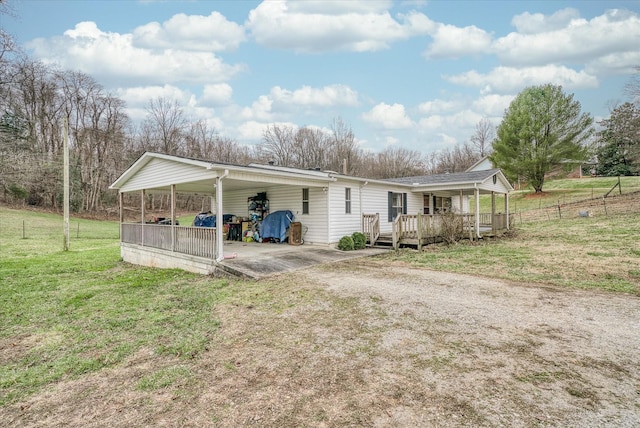 rear view of house with a carport, a yard, and a deck