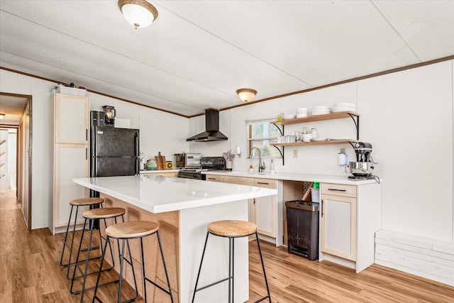 kitchen featuring a breakfast bar, wall chimney range hood, white cabinets, and black appliances