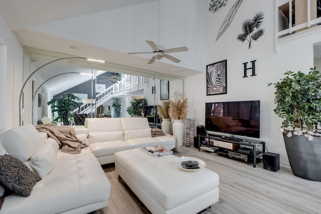 living room with hardwood / wood-style flooring, ceiling fan, and vaulted ceiling