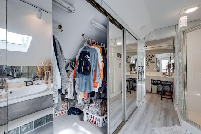 bathroom featuring vaulted ceiling with skylight, independent shower and bath, and hardwood / wood-style floors