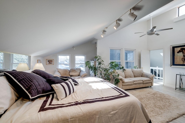 bedroom with rail lighting, vaulted ceiling, ceiling fan, and light hardwood / wood-style flooring