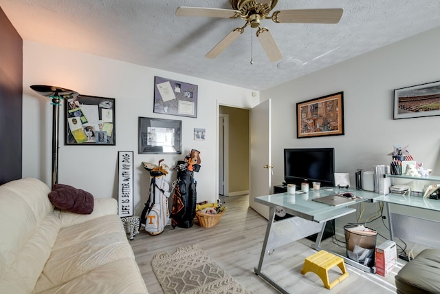 living room featuring ceiling fan, light hardwood / wood-style floors, and a textured ceiling