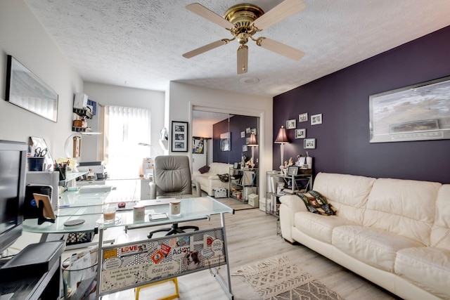 living room featuring ceiling fan, a textured ceiling, and light hardwood / wood-style flooring