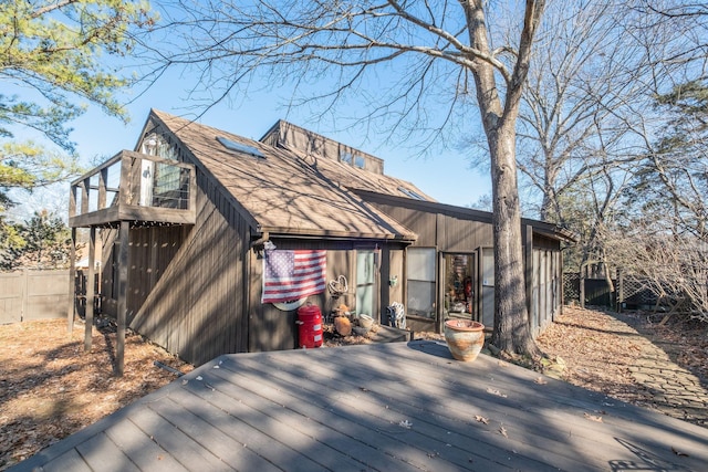 rear view of house featuring a wooden deck and a balcony