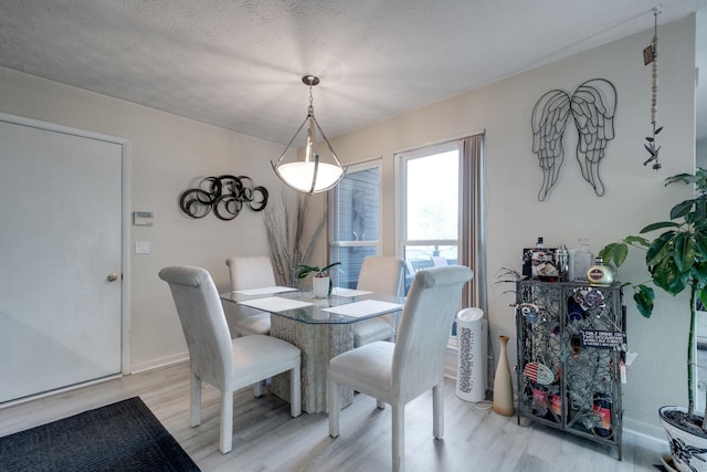 dining area featuring a textured ceiling and light hardwood / wood-style flooring