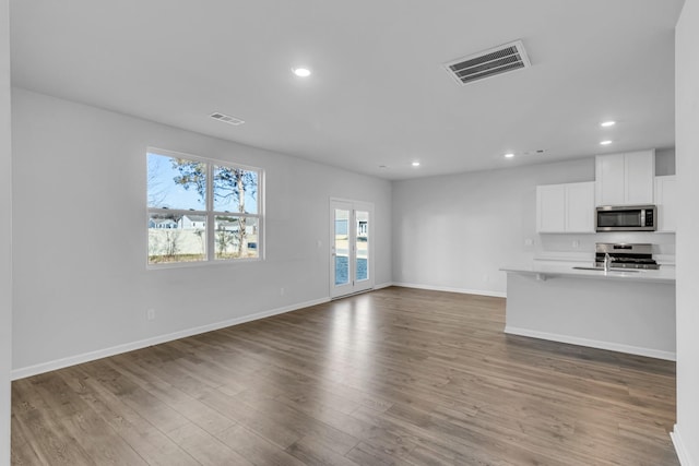 unfurnished living room with hardwood / wood-style flooring and sink