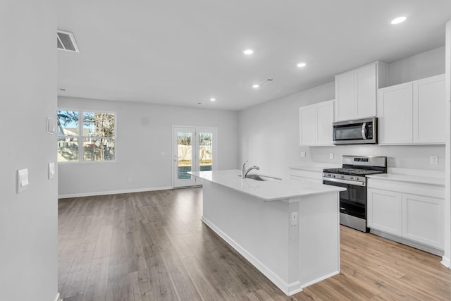 kitchen with sink, stainless steel appliances, an island with sink, and white cabinets