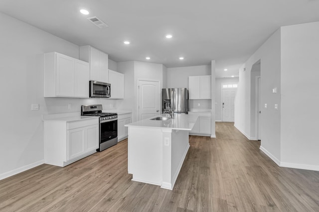 kitchen with sink, a center island with sink, appliances with stainless steel finishes, light hardwood / wood-style floors, and white cabinets