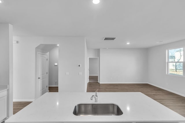 kitchen featuring light stone countertops, sink, white cabinets, and dark hardwood / wood-style floors