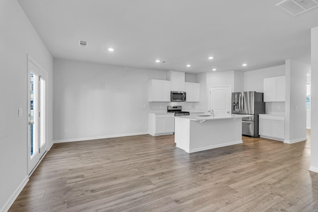 kitchen featuring stainless steel appliances, a kitchen island with sink, light hardwood / wood-style flooring, and white cabinets