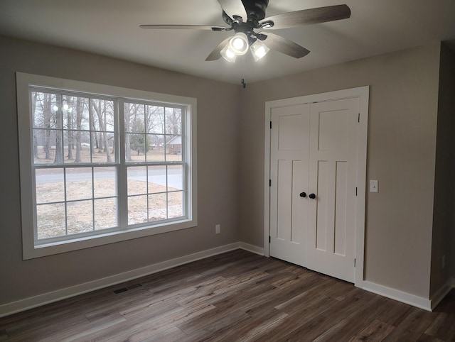 unfurnished bedroom featuring dark hardwood / wood-style floors, ceiling fan, and a closet