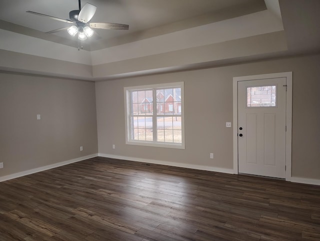 entrance foyer with a raised ceiling, dark wood-type flooring, and ceiling fan