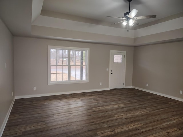 entrance foyer featuring dark wood-type flooring, ceiling fan, and a tray ceiling