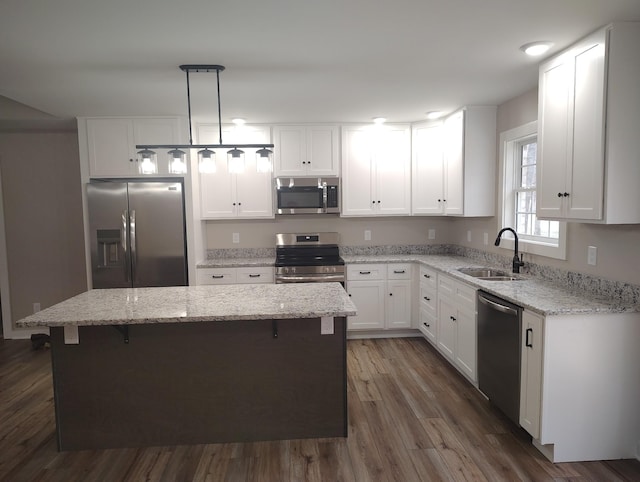 kitchen featuring pendant lighting, sink, appliances with stainless steel finishes, white cabinetry, and a kitchen island